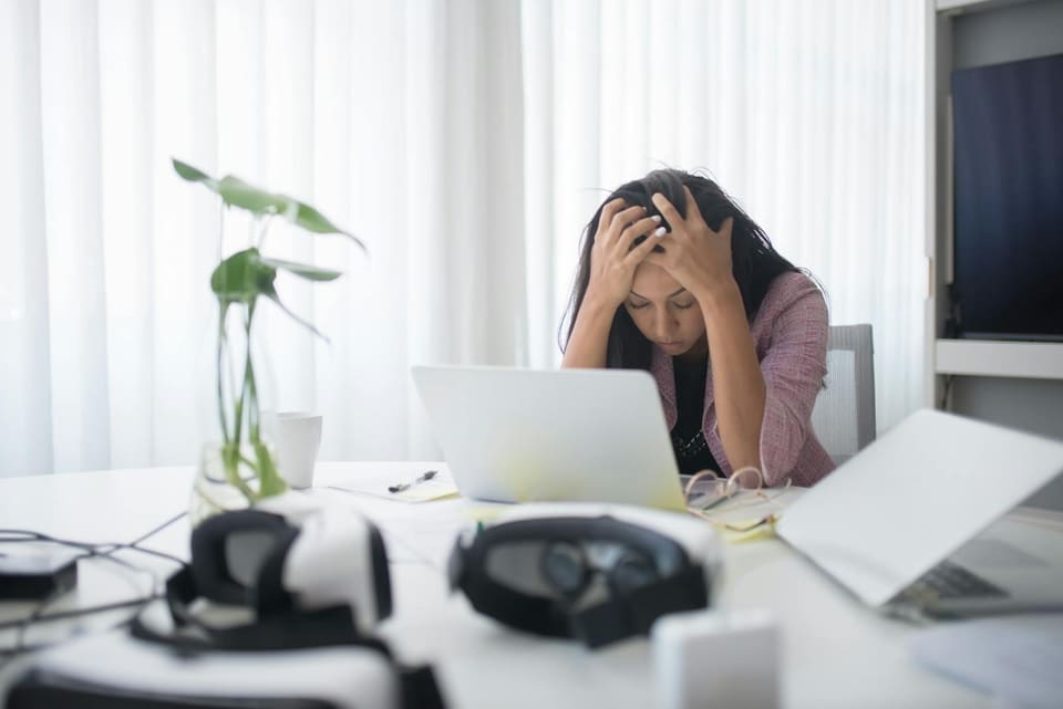 Frustrated South African business owner at her desk with her head in her hands in front of a laptop, overwhelmed by trying to track government tender opportunities scattered across dozens of portals.